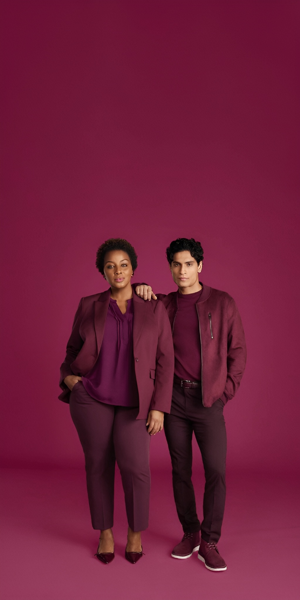 A man and a woman are confidently posing next to each other, casually wearing all-red clothing of different shades.