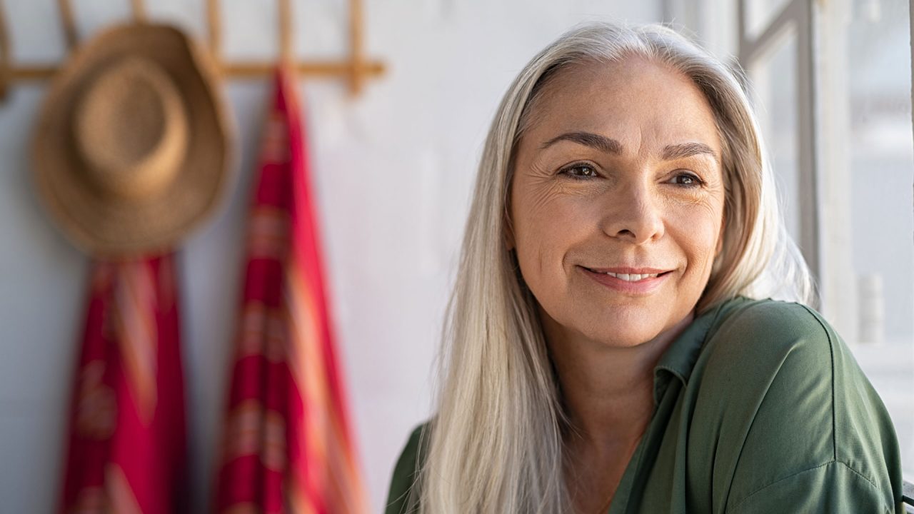 Smiling older woman using dermal filler to target facial lines and wrinkles